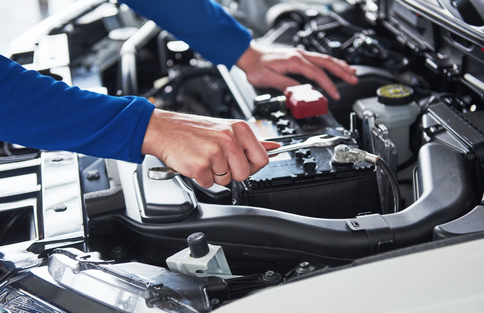 Hands of car mechanic with wrench in garage