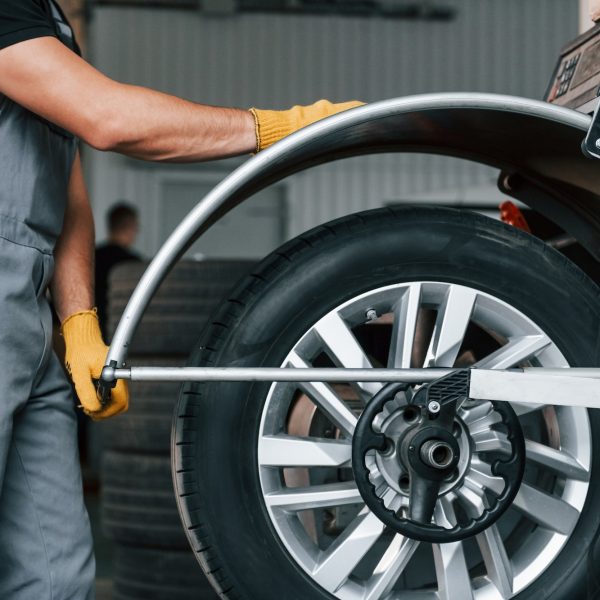 Fixing the tire. Man in uniform is working in the auto service